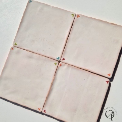 Quatro azulejos quadrados brancos com corações coloridos nos cantos