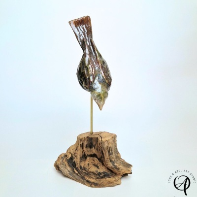 Escultura de pássaro em cerâmica sobre pedestal de madeira com suporte dourado