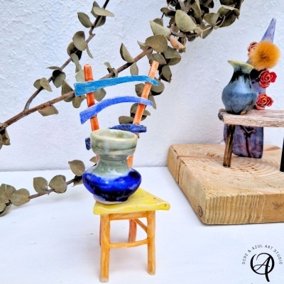 Miniaturas de cadeiras e vasos decorativos coloridos colocados sobre uma superfície branca