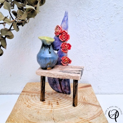 Miniatura decorativa com vaso azul e flores vermelhas sobre mesa de madeira