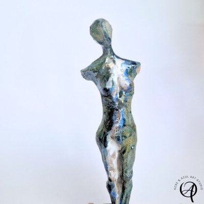 Escultura feminina abstrata em cerâmica com cores verdes, brancas e azuis