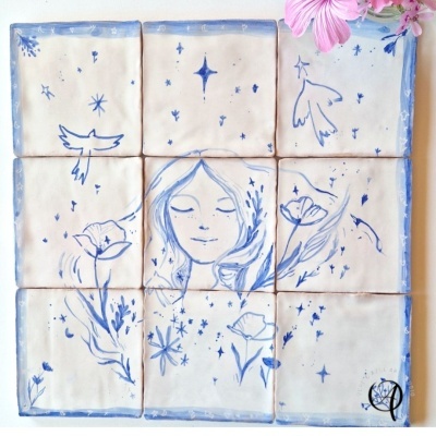 Azulejos cerâmicos brancos pintados à mão com desenhos em azul de uma mulher, flores e pássaros.