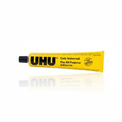 Tubo amarelo de cola universal UHU com tampa preta sobre fundo branco