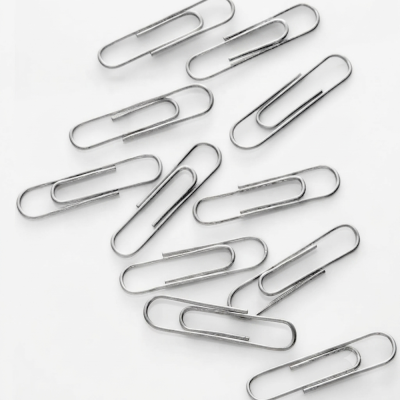 Clips de papel cromados metal espalhados sobre superfície branca