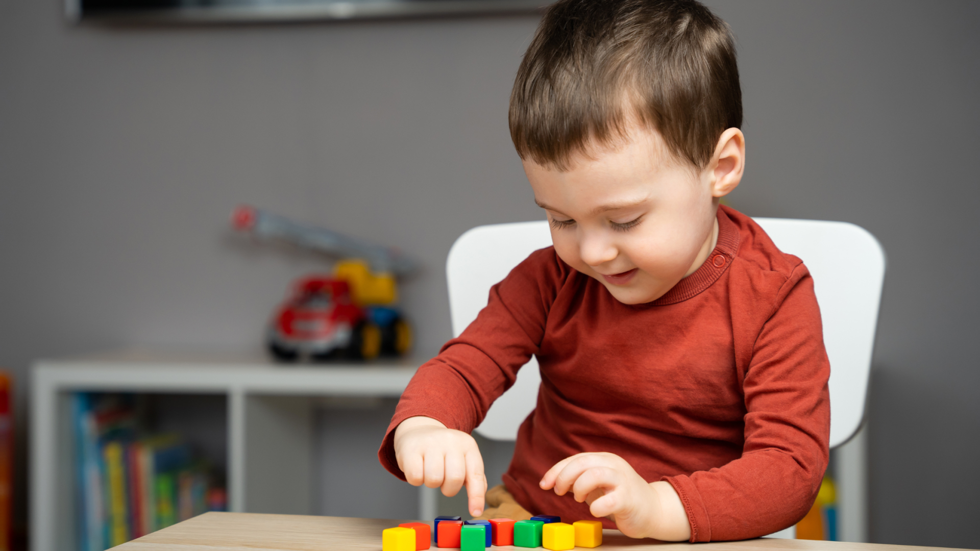 Criança a brincar com blocos coloridos em mesa interior
