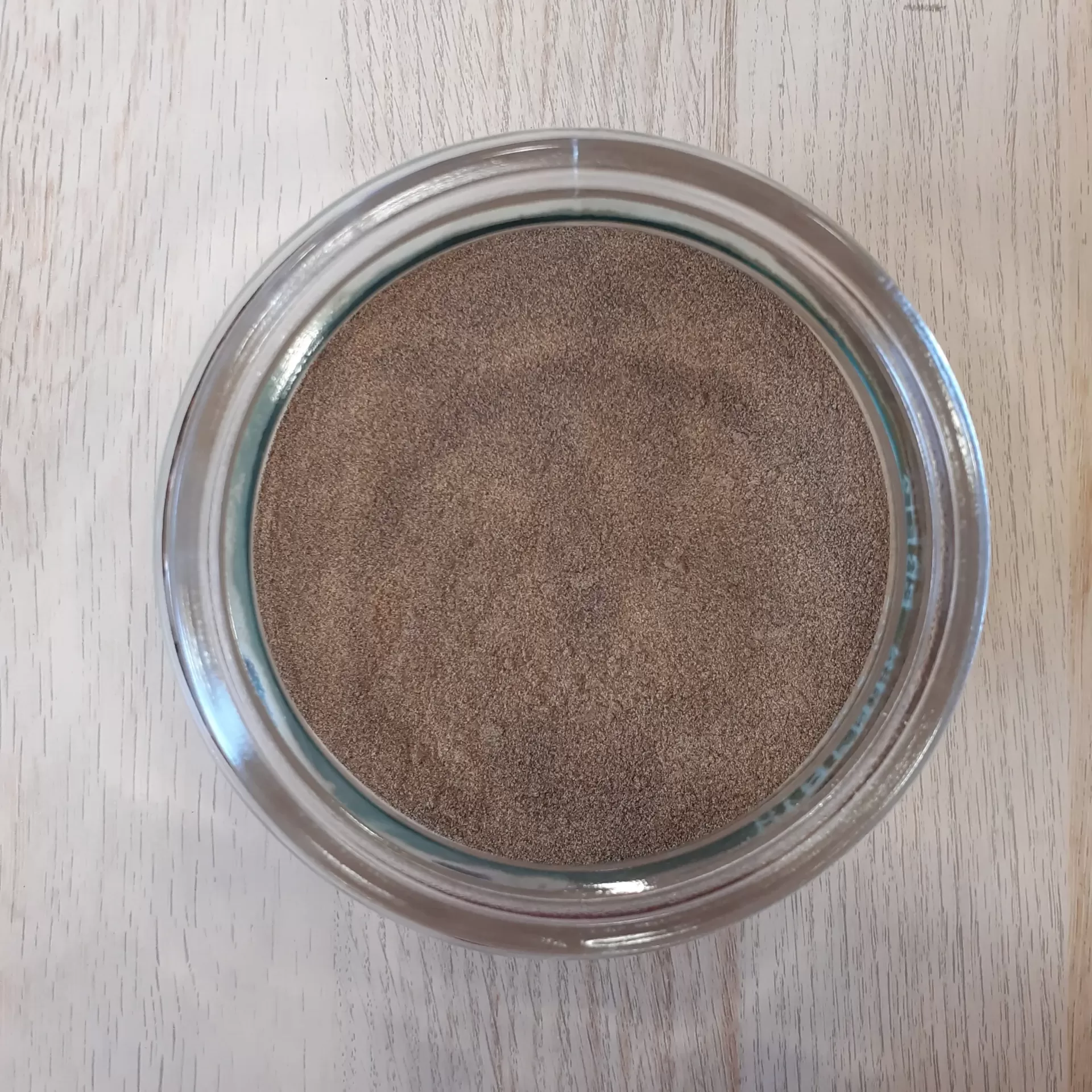 Pimenta Preta em pó BIO a Granel Frasco de vidro com pó castanho visto de cima sobre madeira clara
