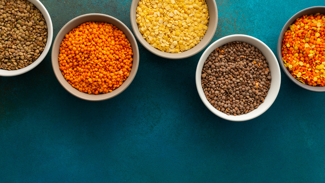 Cinco tigelas com leguminosas diversas sobre fundo azul