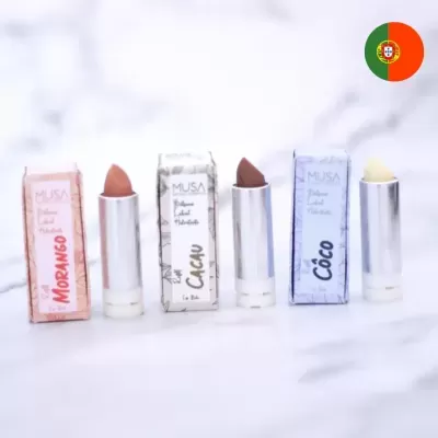 Três batons da marca MUSA em diferentes cores e embalagens alinhados sobre superfície branca.