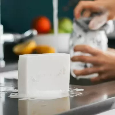 Bloco de gelo numa superfície de aço inoxidável com mão ao fundo