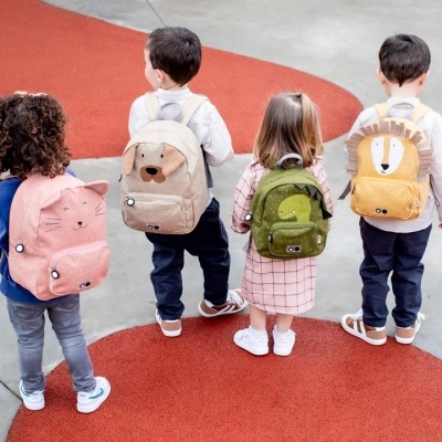 Quatro crianças com mochilas coloridas de animais vistas de costas