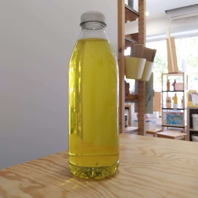 Garrafa plástica com líquido amarelo sobre mesa de madeira em interior