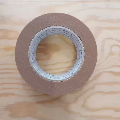 Rolo de fita adesiva castanha sobre madeira clara