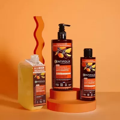 Três produtos Centifolia shampoo anticaspa em fundo laranja, embalagens laranja e preto.