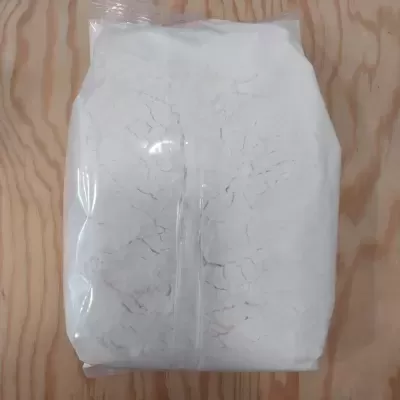 Saco de plástico transparente com pó branco sobre superfície de madeira