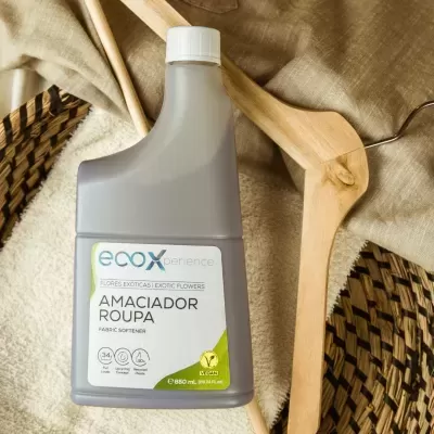 Frasco cinzento de amaciador de roupa Ecoxperience sobre toalha branca com colheres de madeira