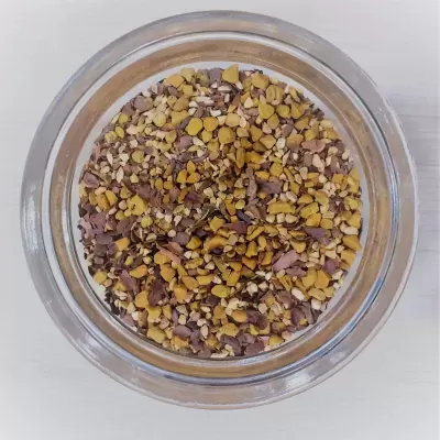 Frasco de vidro com sementes trituradas coloridas visto de cima.