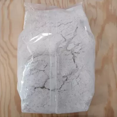 Saco transparente com pó branco sobre madeira clara.