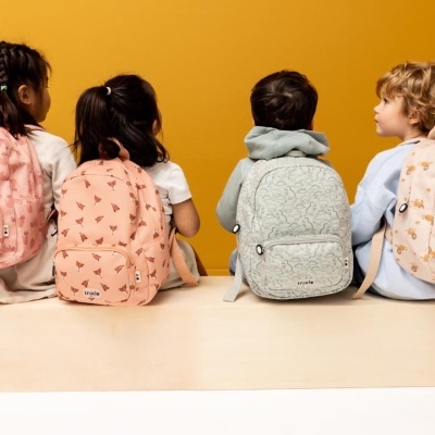 Crianças com mochilas coloridas e padrões florais sentadas de costas