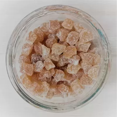 Cumbuquinha de vidro com pedaços de alimento cristalizado amarelo claro polvilhados com açúcar.