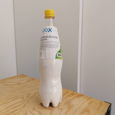 Garrafa de plástico com líquido branco e tampa amarela sobre mesa de madeira