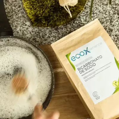 Pacote de bicarbonato de sódio ao lado de panela com espuma sendo mexida