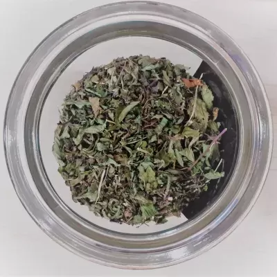 Ervas secas verdes e castanhas num recipiente de vidro