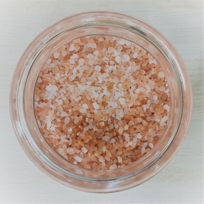Pote de vidro com sal grosso rosa e branco visto de cima