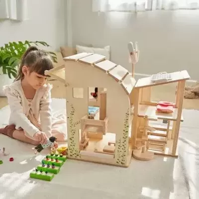 Criança a brincar com casa de madeira para brinquedos num quarto iluminado