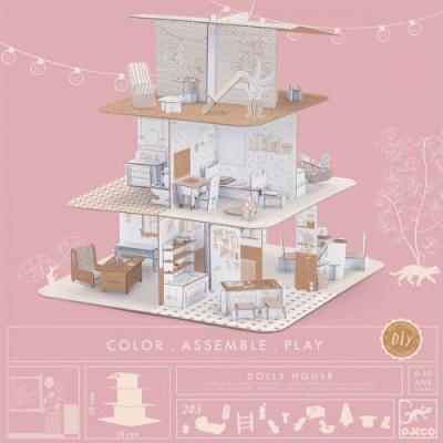 Casa de bonecas em papel/cartão com três andares e mobília em tons neutros, fundo rosa.