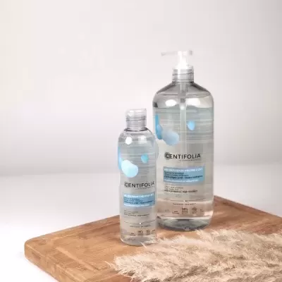 Dois frascos transparentes de gel de limpeza facial Centifolia sobre tábua de madeira clara com planta seca.