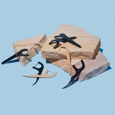 Grampos de cabelo pretos e de madeira clara sobre pedras bege em fundo azul