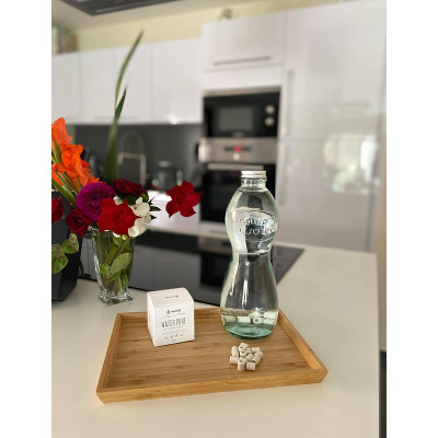 Garrafa de água, pacote branco, comprimidos e flores sobre bandeja de madeira na cozinha