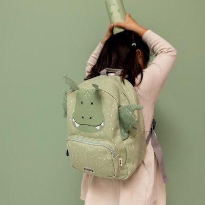 Mochila verde com design de monstro numa criança de costas segurando uma garrafa verde.