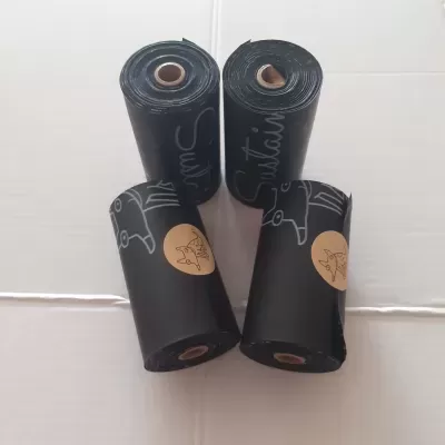 Quatro rolos de sacos pretos com selo castanho mostrando ilustração de cão