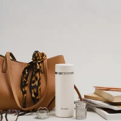 garrafa térmica branca, mala castanha com lenço, óculos e livros