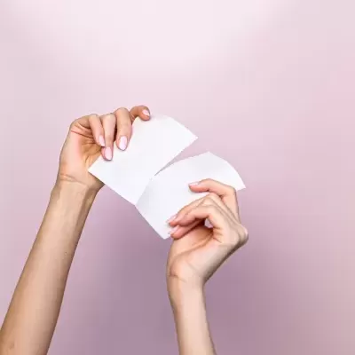 Mãos rasgando papel branco contra fundo rosa