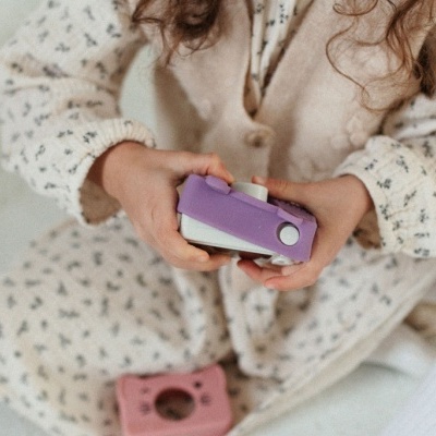 Criança com câmaras instantâneas cor-de-rosa claro e lilás em fundo neutro