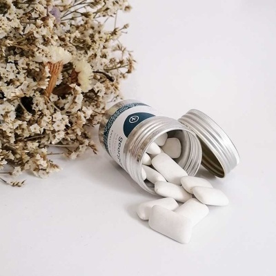 Frasco com pastilhas brancas e flores secas ao lado