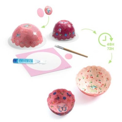 Tigelas em papel machê rosa com padrões florais e borboleta, cola, pincel e molde em papel.