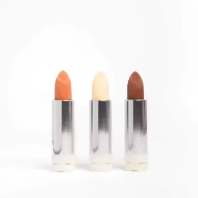 Três batons em tons laranja, branco e castanho com embalagem prateada