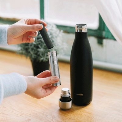 Garrafa térmica preta com infusor metálico em superfície de madeira