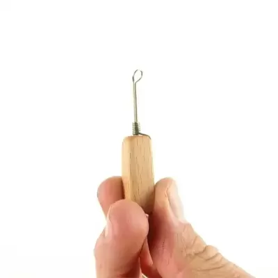 Ferramenta manual com cabo em madeira e ponta metálica em laço segurada por uma mão