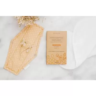 Absorvente menstrual reutilizável amarelo claro com bolinhas e embalagem de cartão em fundo branco