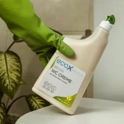 Frasco de WC Creme branco com tampa verde segurado por mão com luva verde