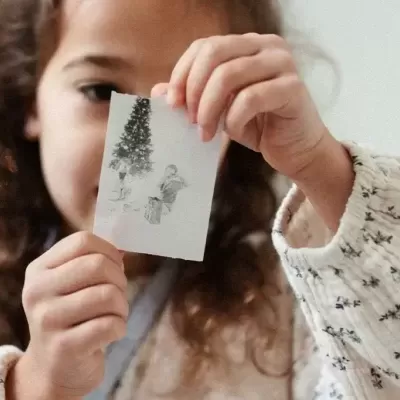 Criança segurando fotografia preta e branca com árvore de Natal
