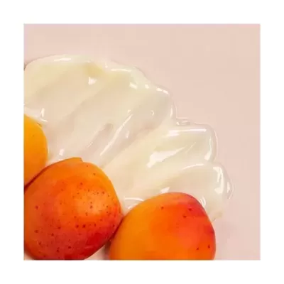 Creme branco cremoso com três frutas alaranjadas tipo damascos sobre fundo rosa claro
