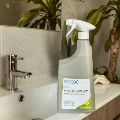 Frasco spray multiusos WC ECOX em cima de bancada próxima a pia com torneira e plantas ao fundo