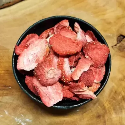 Taça preta com morangos liofilizados fatiados vermelhos