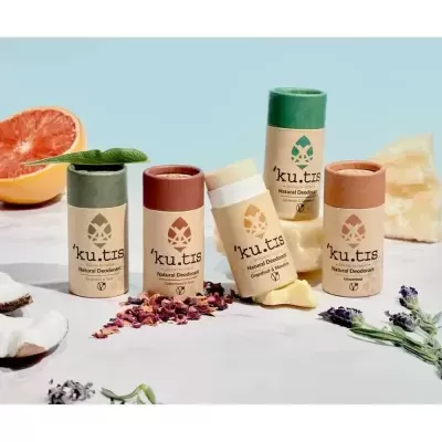 Desodorizantes naturais 'ku.tis' em embalagens recicláveis coloridas com flores e folhas ao redor