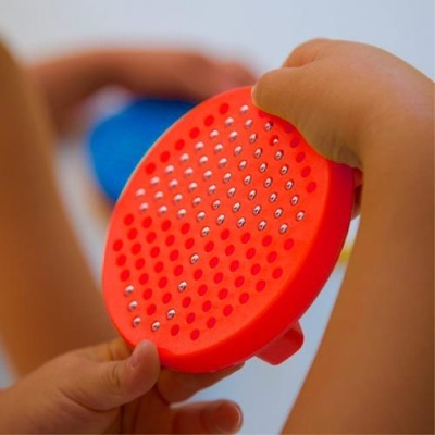 Pente redondo vermelho com pinos de metal nas mãos de uma criança